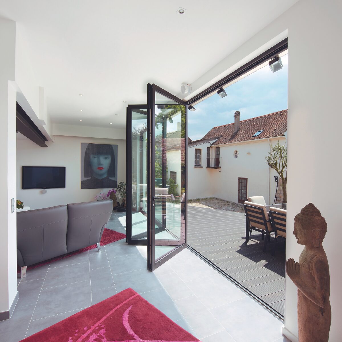 aluminium bifold doors: bifold door half open to allow patio access with sun shining through.